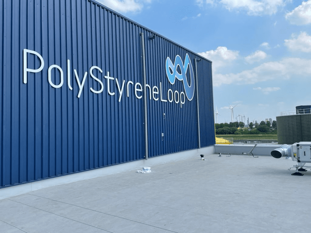 Ein großer blauer Frachtcontainer mit dem „Styropor“-Logo und -Emblem an der Seite, deutlich sichtbar unter klarem Himmel. Auf der rechten Seite ist eine Klimaanlage zu sehen.