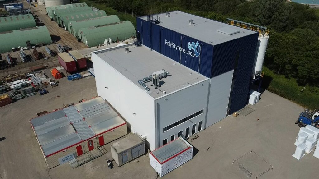 Luftaufnahme einer großen Industrieanlage mit dem Namen „Styropor“ auf dem Gebäude, umgeben von Grünflächen und mehreren kleineren Bauten.
