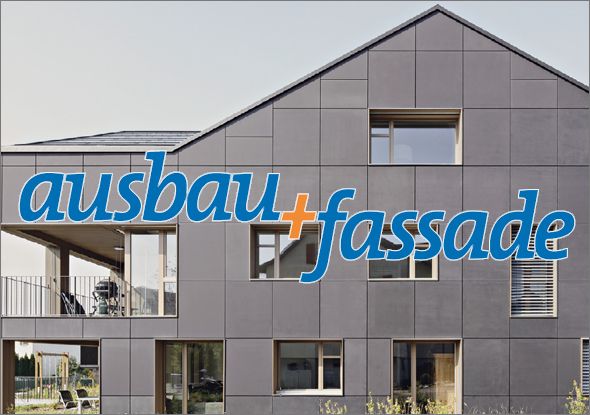 Modernes Gebäude in Modulbauweise mit großen Fenstern und unterschiedlich grauen EPS-Hartschaumplatten. Die Worte „ausbau+fassade“ sind in großen, bunten Buchstaben über die